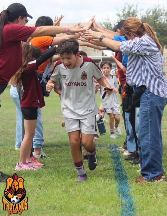 Un jugador de Troyanos entra a la cancha entre las manos levantadas de los papás